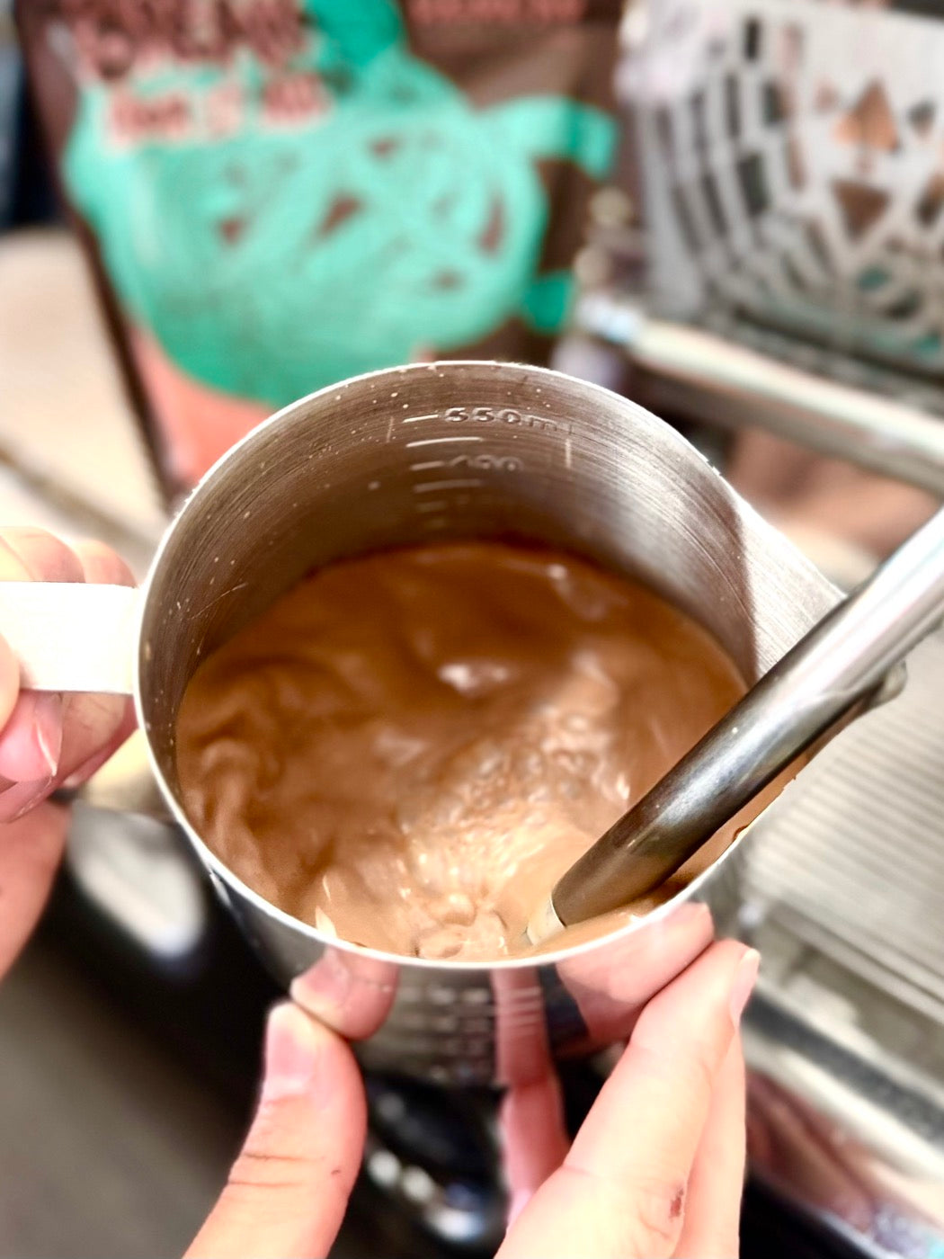 Chocolate being steamed in a pitcher