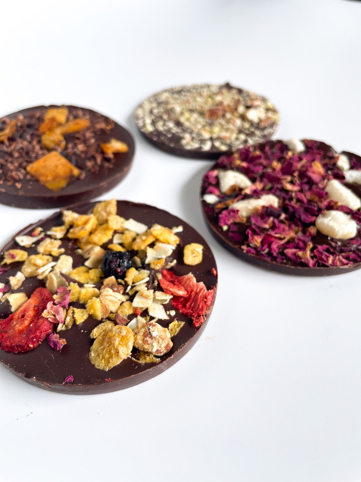 Chocolate discs decorated with fruit, flowers and nuts